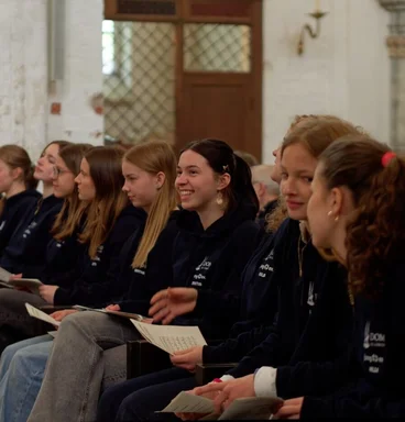 Junge Menschen sitzen in einer Reihe in einer Kirche