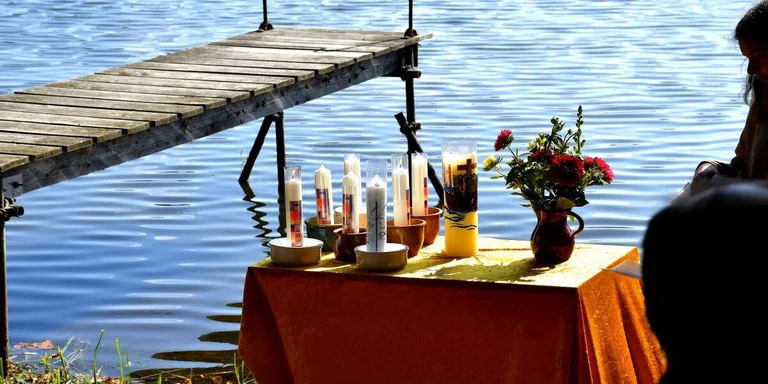 Holzsteg am See mit Tisch voller Taufkerzen