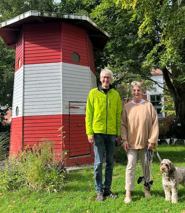 Ein Mann und eine Frau stehen lächelnd vor einem Leuchtturm.