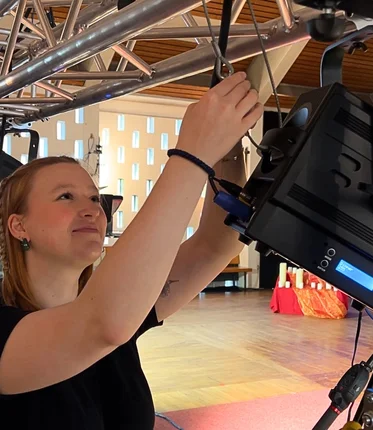 Eine junge Frau arbeitet an einem großen Scheinwerfer.