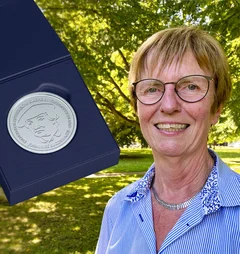 Eine Frau zeigt eine Medaille