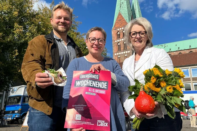 Drei Menschen schuen auf dem Lübecker Markt stehend in die Kamera