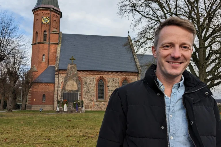 Ein Mann steht vor einer Kirche