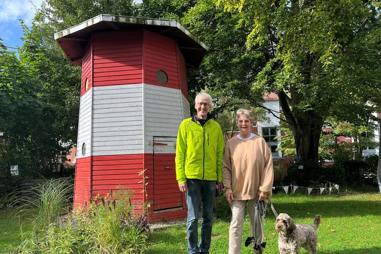 Ein Mann und eine Frau stehen lächelnd vor einem Leuchtturm.