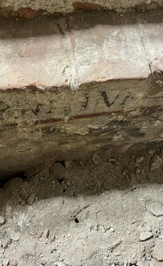 Seitenwand einer Gruft mit Inschrift und farbigen Wandmalereien.