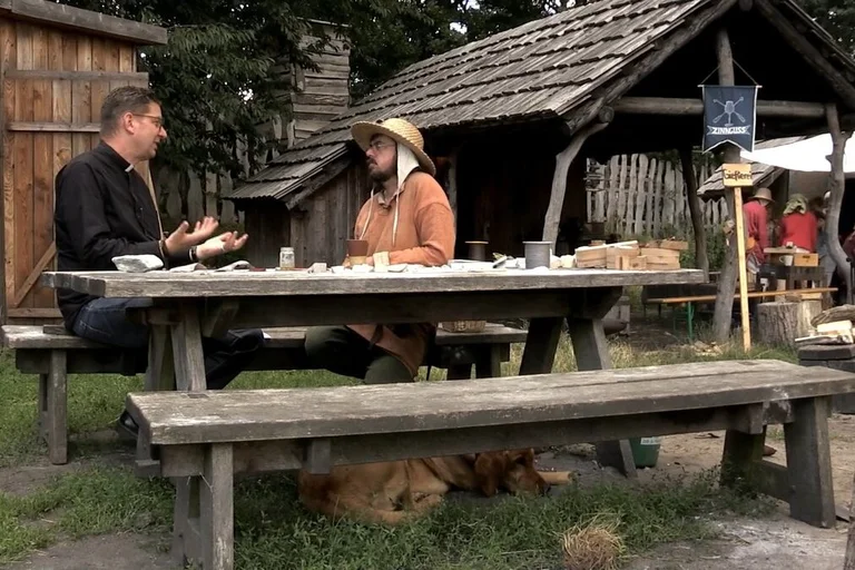 Zwei Männer sitzen an einem historischen Tisch.