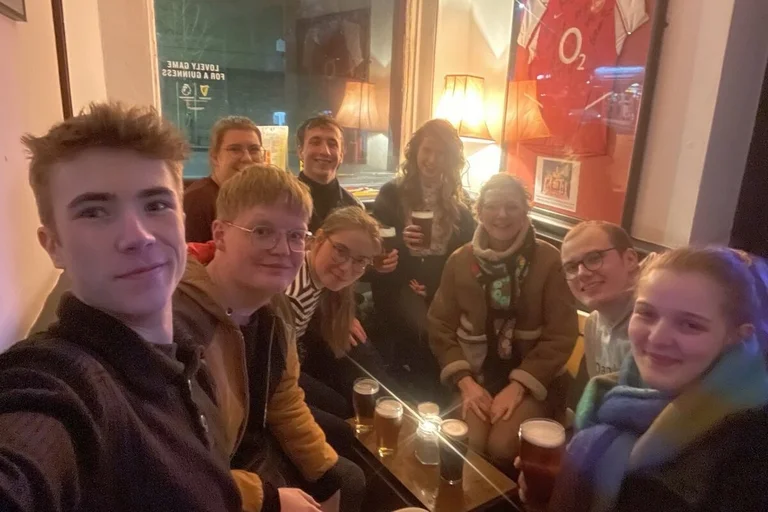 Selfie von vielen jungen Leuten an einem Tisch in einem Pub.