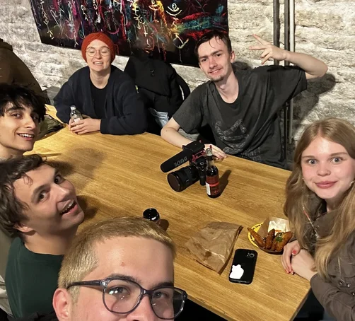 Eine Gruppe junger Menschen macht ein Selfie an einem Tisch.