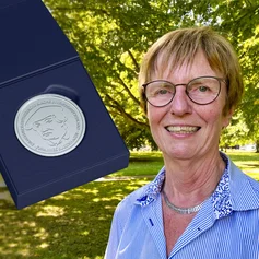 Eine Frau zeigt eine Medaille