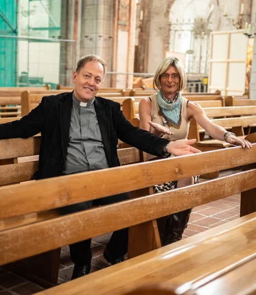 Ein Mann und eine Frau sitzen auf Kirchenbänken