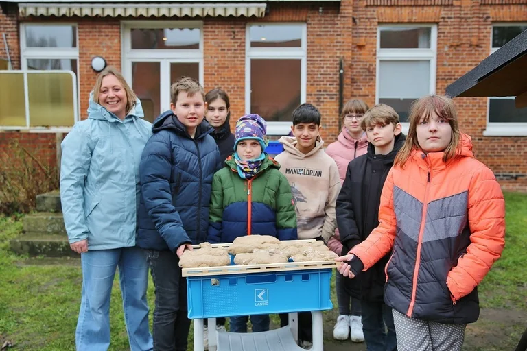 Sieben Jugendliche und eine Frau stehen am Lehmbackofen 