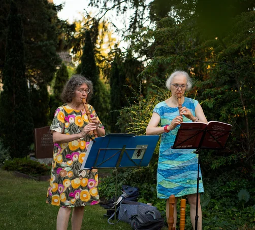 Zwei Frauen spielen Flöte im Grünen.