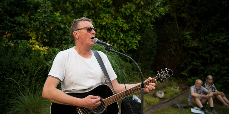 Singender Mann mit Gitarre im Grünen