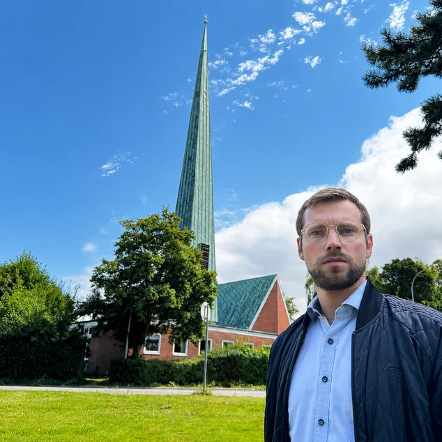 Mann steht vor einer Kirche