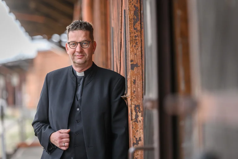 Ein Mann steht im Hafen und schaut in die Kamera. 