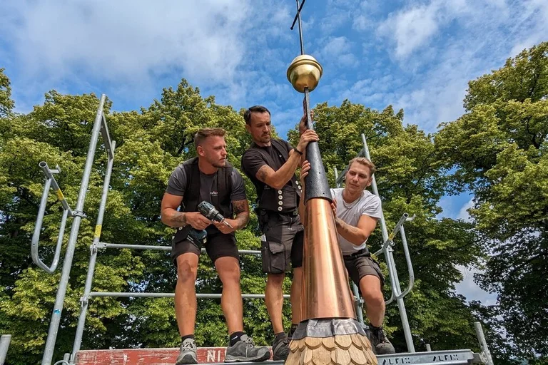 Männer arbeiten an einem Kirchturm