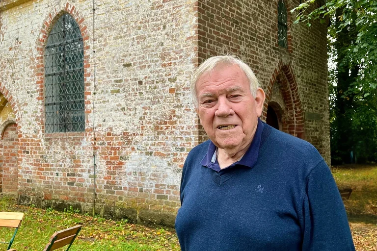 Ein älterer Mann vor einer Kirche