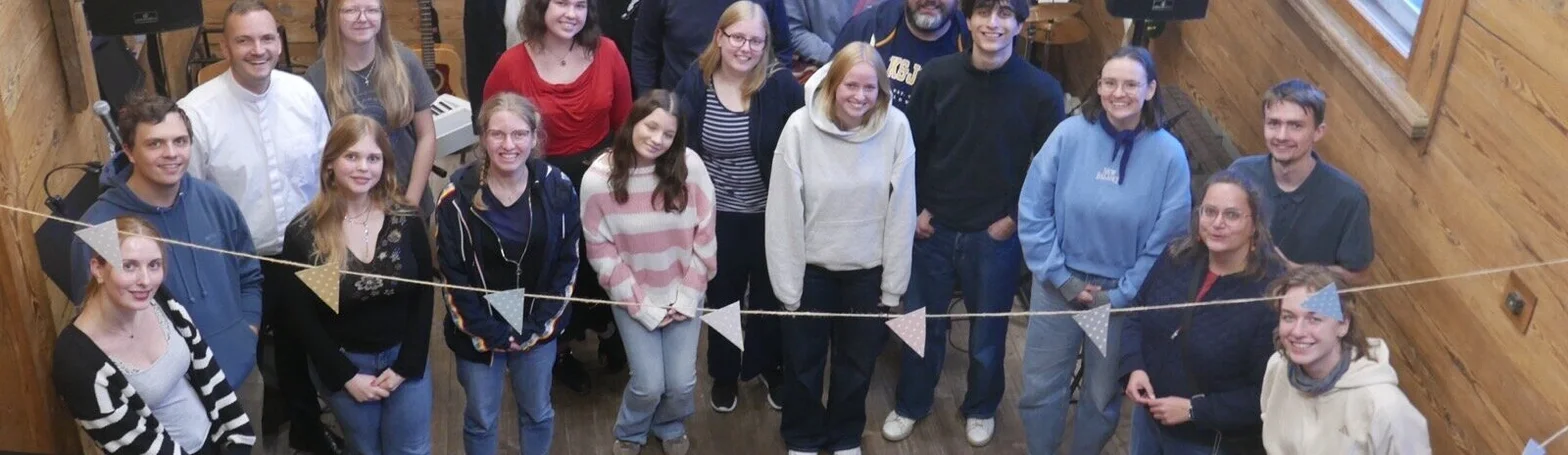Eine Gruppe von jungen Menschen steht in einem mit Holz verkleideten Raum