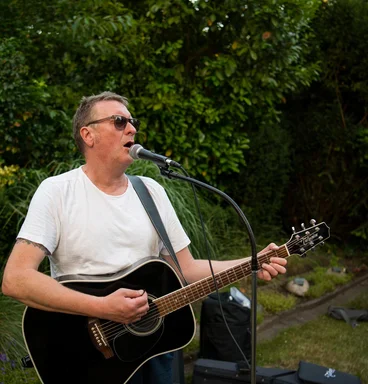 Singender Mann mit Gitarre im Grünen