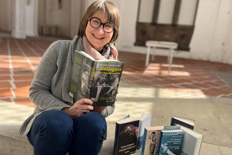 Eine Frau sitzt auf einer Treppe in einer Kirche mit einem Buch in der Hand