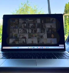 Ein Laptop steht auf einem Schreibtisch mit Garten und blauem Himmel im Hintergrund.