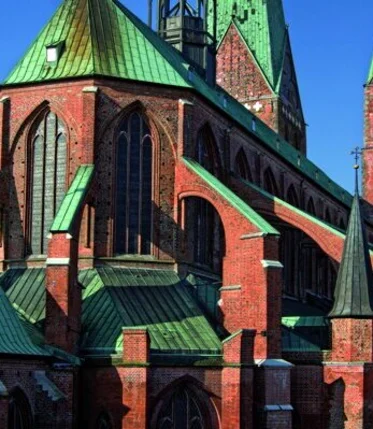 Eine große Backsteinkirche mit Kirchenschiff und Türmen und grünen Kuperdächern