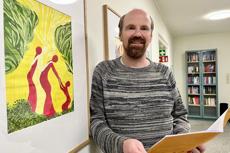 Ein Mann mit Bart lächelt den Betrachter an.