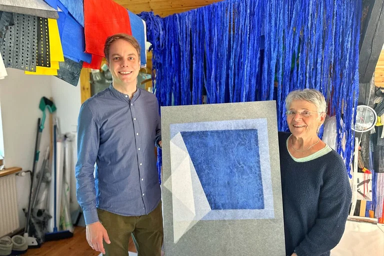 Zwei Personen stehen in einem Atelier an einem Bild.