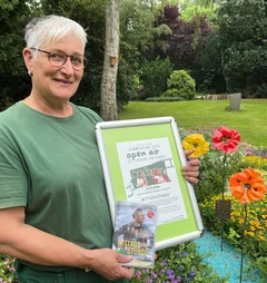 Eine Frau steht mit einem Plakat auf einem Friedhof.