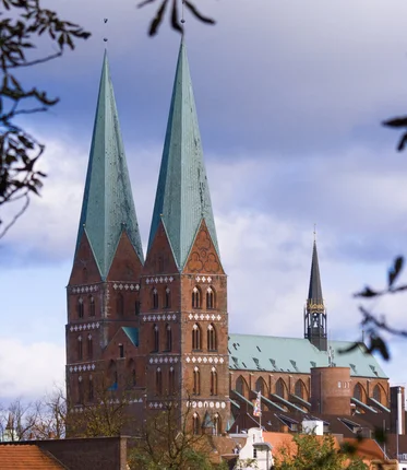 Eine große Backsteinkirche mit zwei hohen, grünen Kupfertürmen