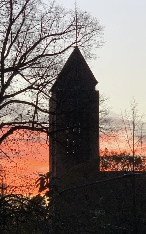 Ein Kirchturm - Im Hintergrund Abendrot und Dämmerung