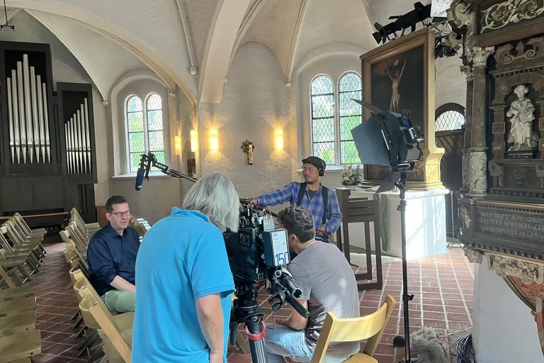 Blick in eine Kirche, in der ein TV-Interview stattfindet.