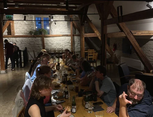 Menschen sitzen an einem einem langen Holztisch und essen