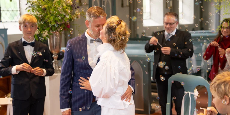 Ein Mann und eine Frau in Hochzeitsgaderobe küssen sich