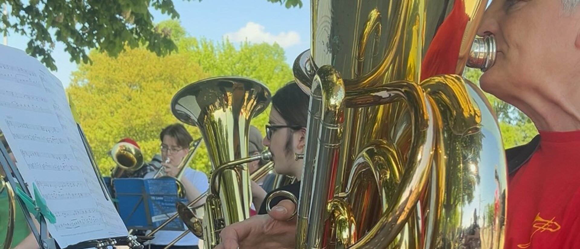 Mehrere Personen spielen im Freien in einem Posaunenchor