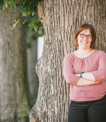 Pastorin Pfeifer lehnt an einem Baum