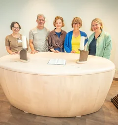Gruppe an Menschen steht hinter dem neuen Altar im Raum der Stille