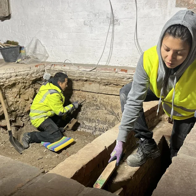 Ein Mann und eine Frau in gelben Warnwesten arbeiten in einer Ausgrabungsstelle.
