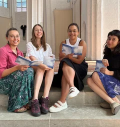 Vier frauen sitzen auf einer Treppe und lächeln in die Kamera.
