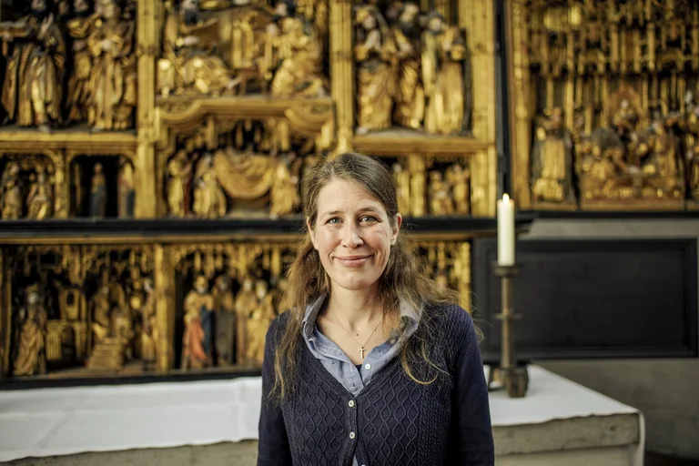 Eine Frau steht lächelnd in einer Kirche