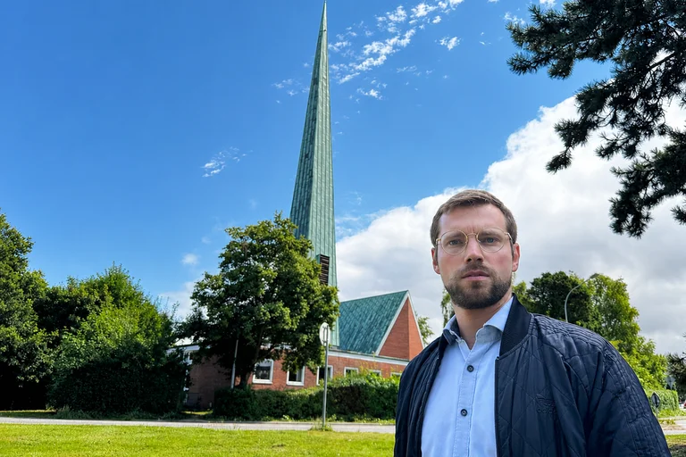 Mann steht vor einer Kirche