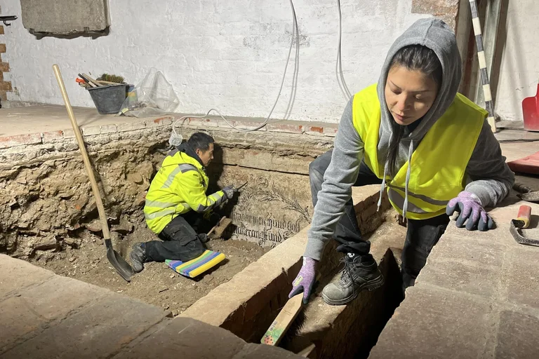 Ein Mann und eine Frau in gelben Warnwesten arbeiten in einer Ausgrabungsstelle.