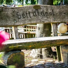 Holzbank mit plattdeutscher Schrift: Sett di daal