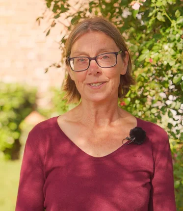 Eine Frau steht im Grünen.