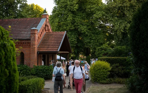 Menschen vor einer Friedhofskapelle in Abendlicht