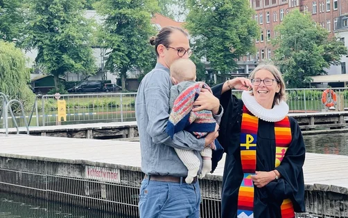 Der kleine Ferdinand verschläft seine Taufe in den Armen von Papa Christoph Unglaub. Rechts Pastorin Nicola Nehmzow.