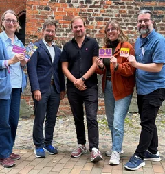 Fünf Menschen  schauen fröhlich in die Kamera