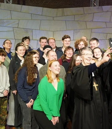 Eine Bischöfin macht ein Selfie mit einer großen Gruppe Menschen in einer Kirche.