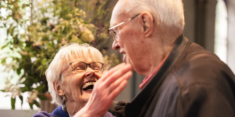 Älteres Paar lacht sich in einer Kirche fröhlich an.