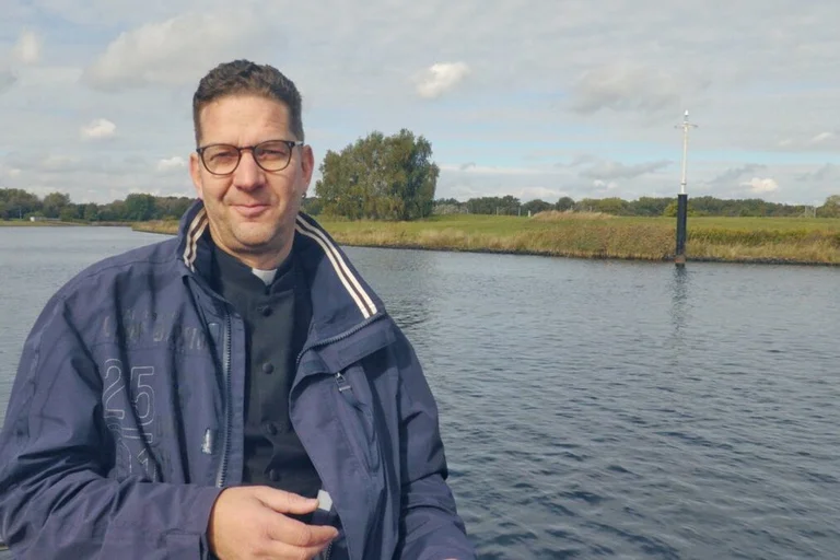 Ein Mann steht vor einer Landschaft und einem Fluss. 